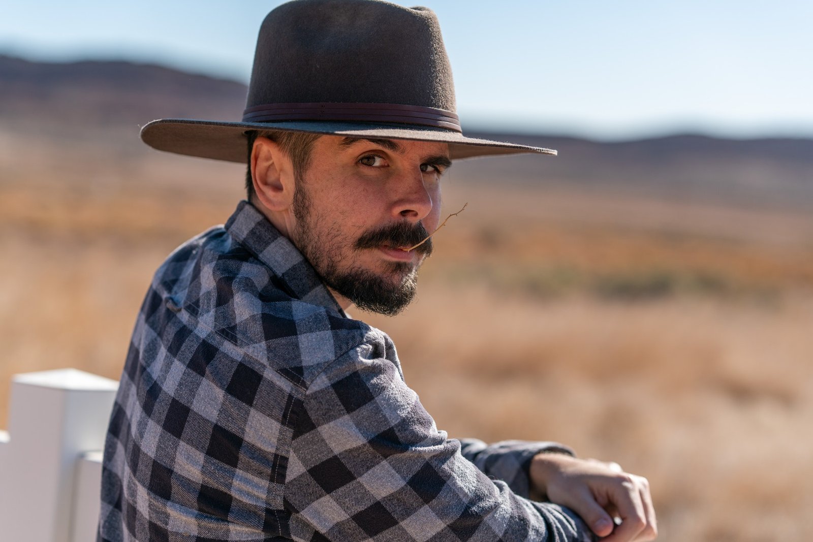 Cowboy with grey hat, moustache and checked shirt